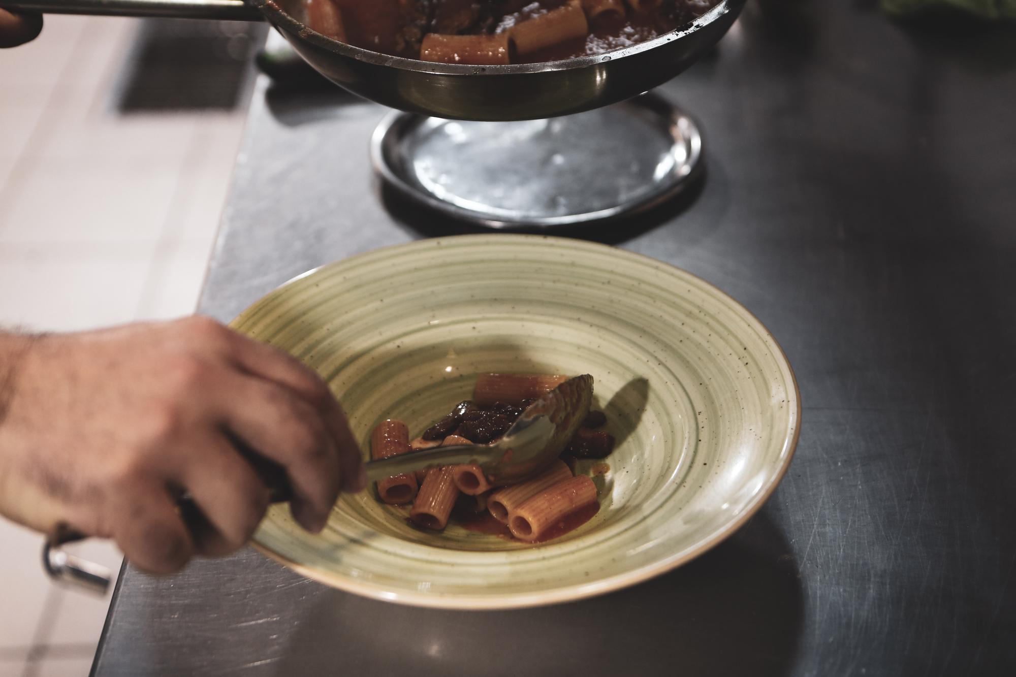 hands plating a composed dish on a ceramic plate